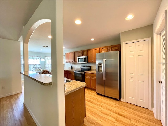 kitchen with brown cabinetry, stainless steel appliances, light wood finished floors, and recessed lighting