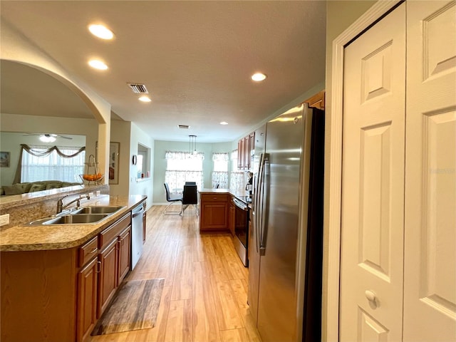 kitchen with appliances with stainless steel finishes, open floor plan, visible vents, and a sink