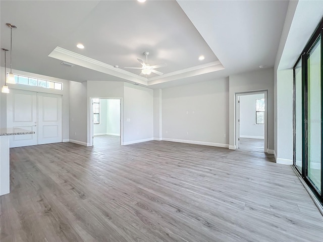 unfurnished living room featuring a raised ceiling, ceiling fan, and light wood-type flooring