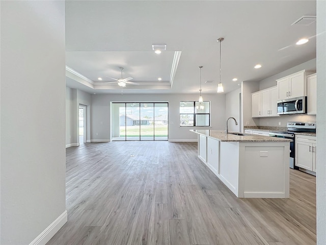 kitchen with a center island with sink, sink, light hardwood / wood-style floors, white cabinetry, and stainless steel appliances