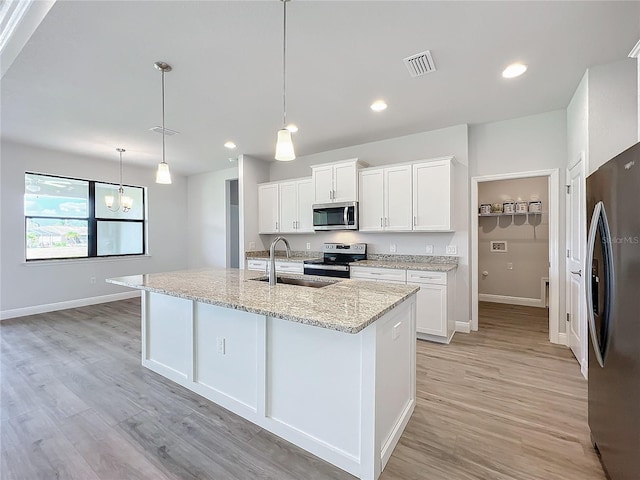 kitchen with white cabinets, sink, decorative light fixtures, light hardwood / wood-style floors, and stainless steel appliances