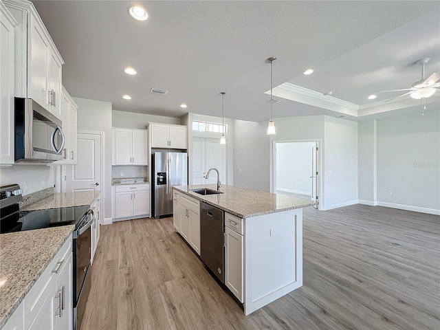 kitchen with pendant lighting, a kitchen island with sink, light wood-type flooring, appliances with stainless steel finishes, and white cabinetry