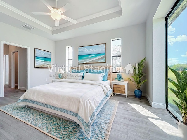 bedroom featuring a raised ceiling, light hardwood / wood-style flooring, ceiling fan, and ornamental molding