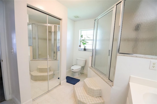 bathroom featuring toilet, vanity, tile patterned floors, and a shower with door