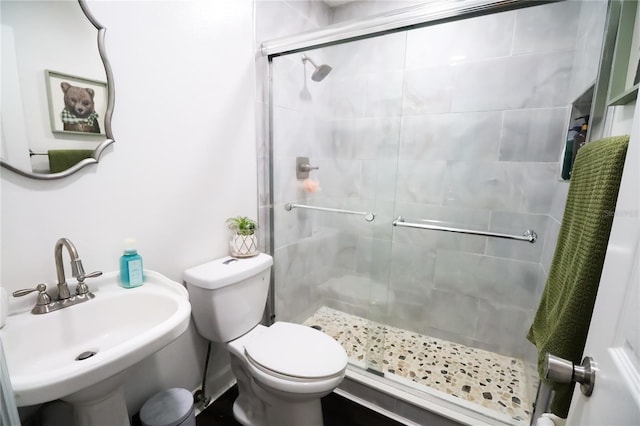 bathroom with toilet, a shower with shower door, and sink