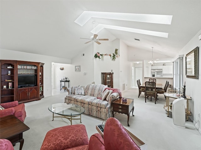 living room with a skylight, light carpet, high vaulted ceiling, and ceiling fan with notable chandelier