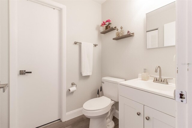 bathroom with hardwood / wood-style flooring, vanity, and toilet