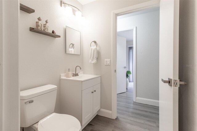 bathroom with hardwood / wood-style floors, vanity, and toilet