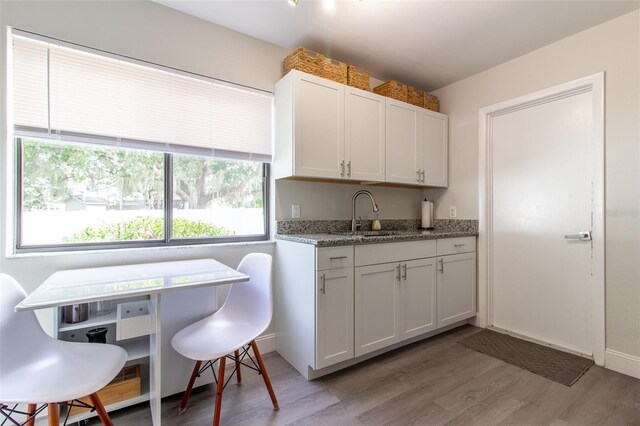 kitchen featuring stone counters, white cabinetry, sink, and light hardwood / wood-style floors