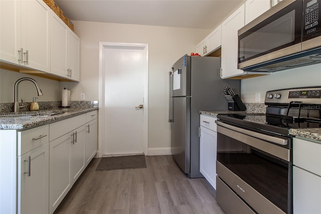 kitchen featuring white cabinetry, sink, light wood-type flooring, and appliances with stainless steel finishes