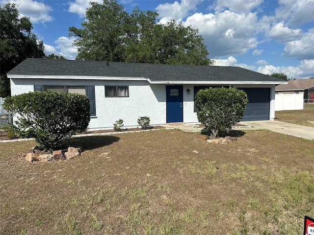 view of front facade with a garage, fence, a front yard, stucco siding, and driveway