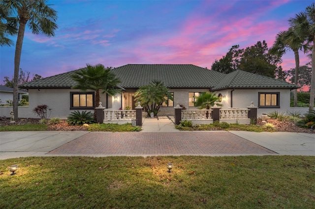 view of front facade with a lawn, a fenced front yard, stucco siding, and a tile roof