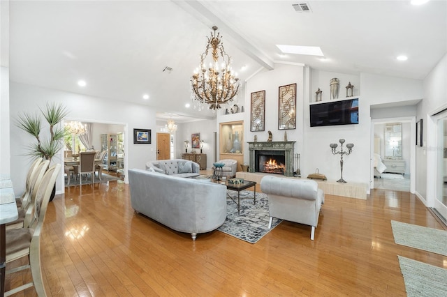 living room with light hardwood / wood-style floors, lofted ceiling with skylight, and a notable chandelier