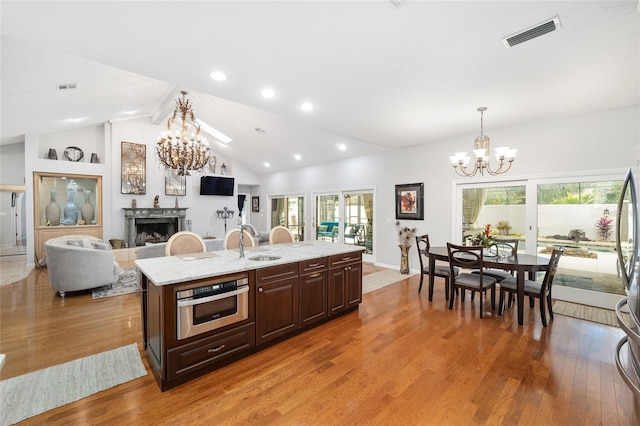 kitchen featuring a center island with sink, lofted ceiling with beams, a healthy amount of sunlight, and light hardwood / wood-style flooring