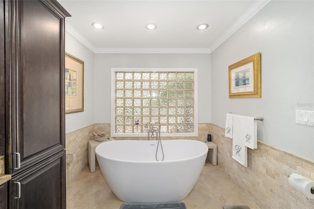 bathroom featuring a tub to relax in, tile patterned flooring, tile walls, and ornamental molding