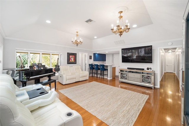 living room with wood-type flooring, crown molding, a tray ceiling, and an inviting chandelier