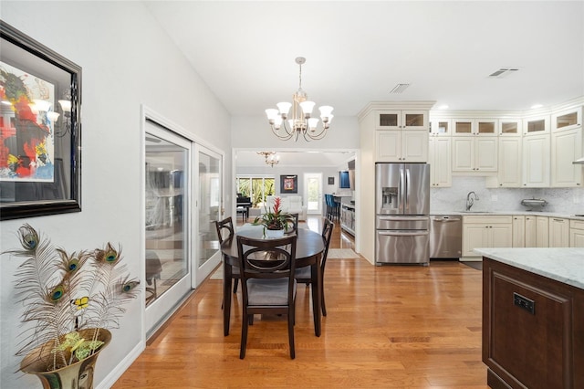 dining area featuring a chandelier, light wood-type flooring, and sink