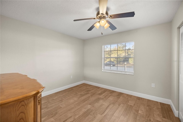 empty room featuring ceiling fan, light hardwood / wood-style flooring, and a textured ceiling