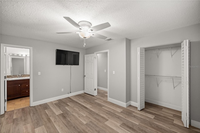 unfurnished bedroom featuring a textured ceiling, ceiling fan, ensuite bathroom, and a closet