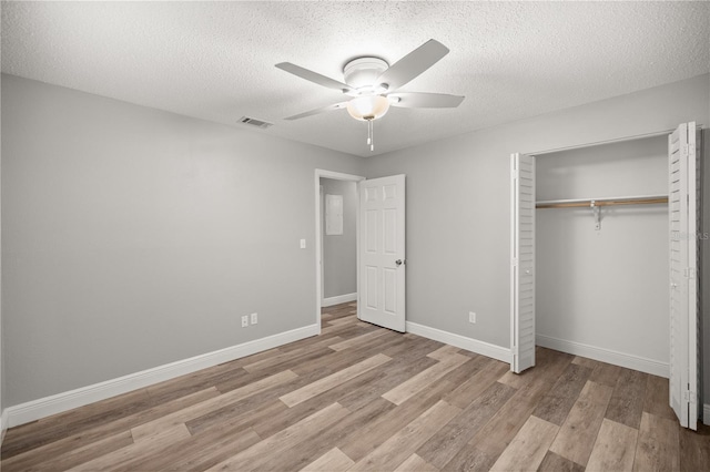 unfurnished bedroom with a textured ceiling, ceiling fan, a closet, and light hardwood / wood-style floors