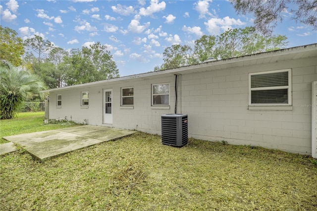 rear view of property featuring a patio area, a lawn, and central AC