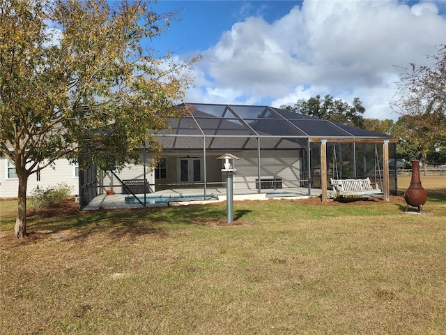 rear view of house with a yard and glass enclosure