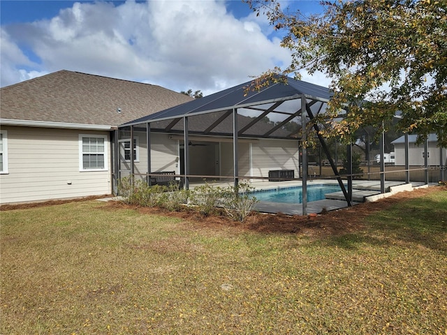 view of pool with glass enclosure and a yard