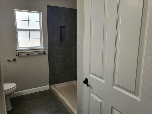 bathroom with tile patterned floors, toilet, and a tile shower