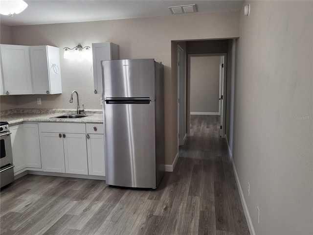 kitchen with hardwood / wood-style floors, sink, white cabinets, and stainless steel appliances