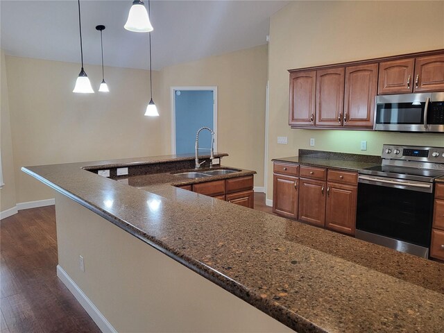 kitchen with hanging light fixtures, sink, stainless steel appliances, and dark hardwood / wood-style floors