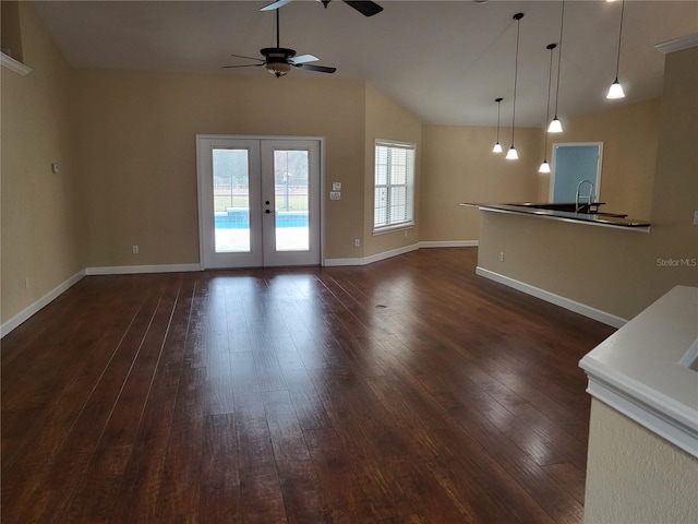 unfurnished living room with french doors, dark hardwood / wood-style flooring, vaulted ceiling, and ceiling fan