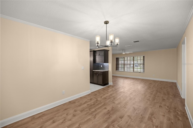 unfurnished living room with ceiling fan with notable chandelier, light hardwood / wood-style floors, and crown molding