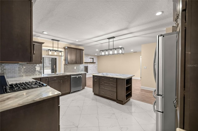 kitchen with decorative light fixtures, a kitchen island, dark brown cabinetry, and stainless steel appliances