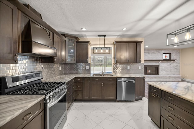 kitchen with custom exhaust hood, sink, appliances with stainless steel finishes, decorative light fixtures, and dark brown cabinetry