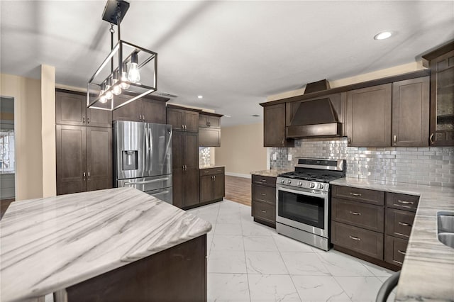 kitchen featuring tasteful backsplash, premium range hood, pendant lighting, dark brown cabinets, and appliances with stainless steel finishes