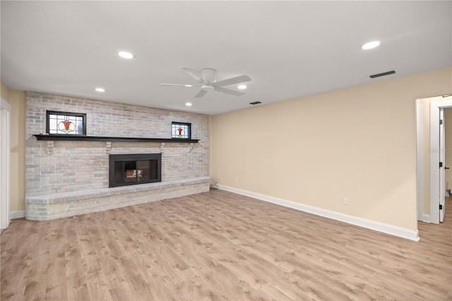 unfurnished living room featuring ceiling fan, a fireplace, and light wood-type flooring