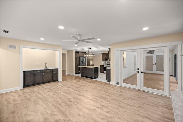 unfurnished living room with ceiling fan, light wood-type flooring, sink, and french doors