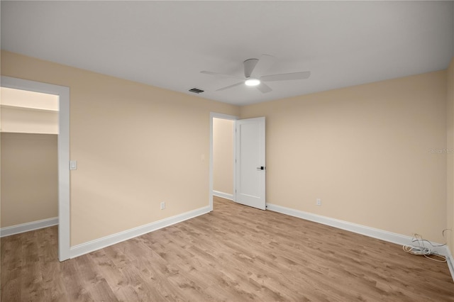 unfurnished bedroom with a spacious closet, a closet, ceiling fan, and light hardwood / wood-style flooring