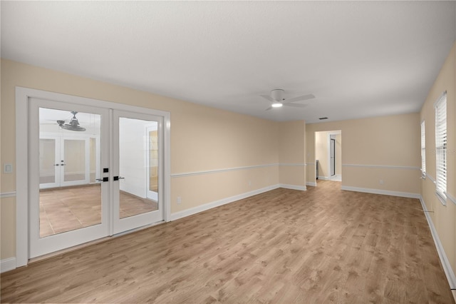 empty room with ceiling fan, light wood-type flooring, and french doors