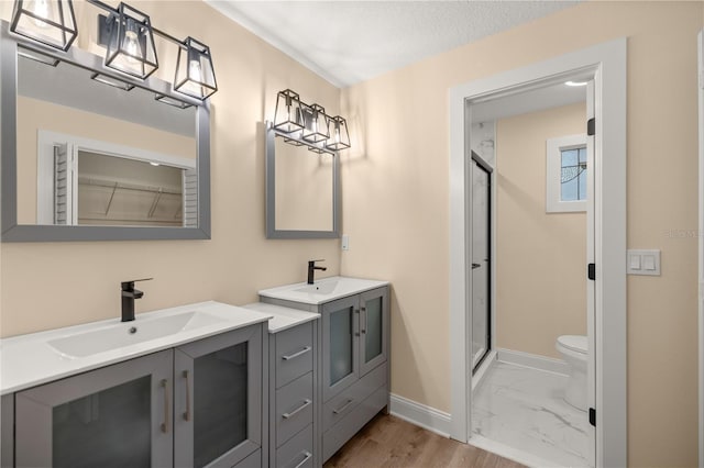 bathroom with an enclosed shower, a textured ceiling, vanity, hardwood / wood-style floors, and toilet