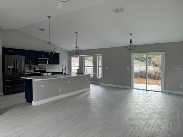 kitchen featuring vaulted ceiling, stainless steel appliances, a wealth of natural light, and an island with sink