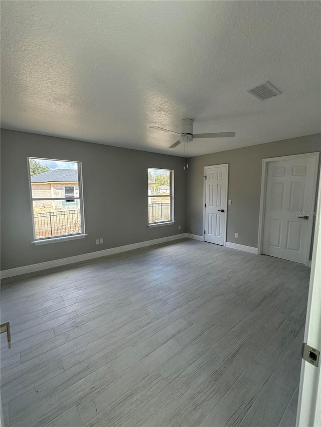 unfurnished room featuring a textured ceiling, a wealth of natural light, and light hardwood / wood-style flooring