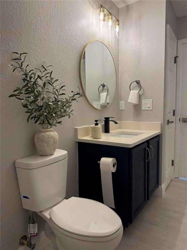 bathroom featuring wood-type flooring, vanity, and toilet