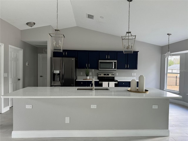 kitchen featuring a large island with sink, stainless steel appliances, vaulted ceiling, and blue cabinets