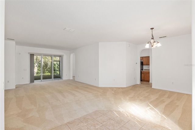 empty room featuring light colored carpet and an inviting chandelier