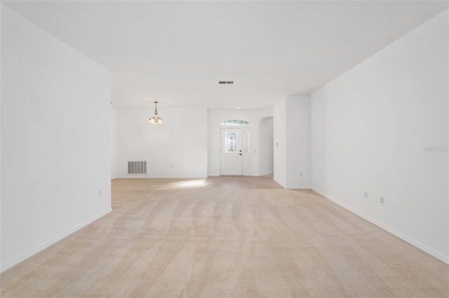 unfurnished living room with light colored carpet and a chandelier