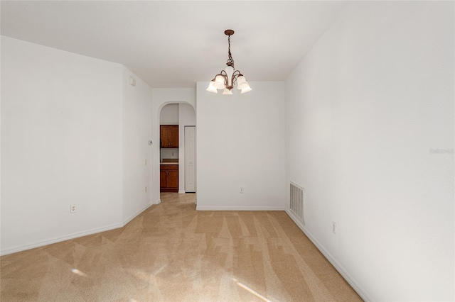 carpeted spare room with a chandelier