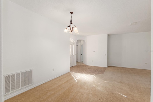 carpeted spare room with a chandelier and a textured ceiling