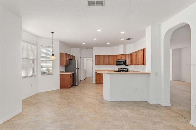 kitchen featuring kitchen peninsula, appliances with stainless steel finishes, a textured ceiling, and pendant lighting