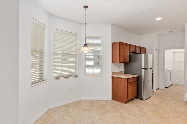 kitchen featuring pendant lighting, a textured ceiling, washer / clothes dryer, and stainless steel refrigerator